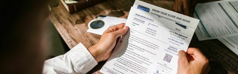 A man applying for a loan holding a credit score report with two hands