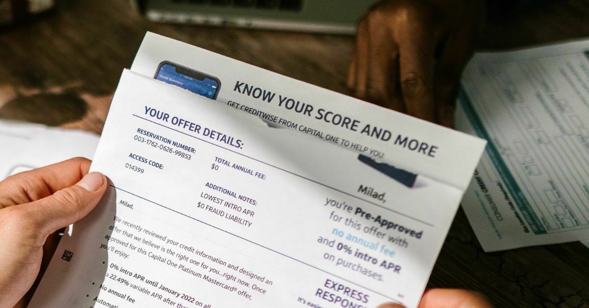 A hand holding a form showing a credit score report