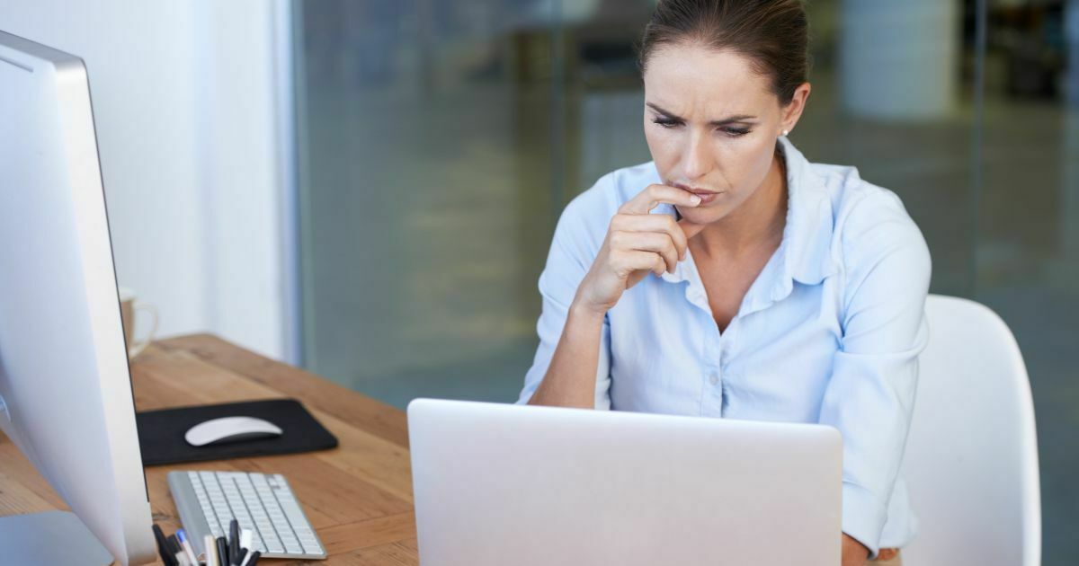 A woman intently looking at a laptop on a table in front of her