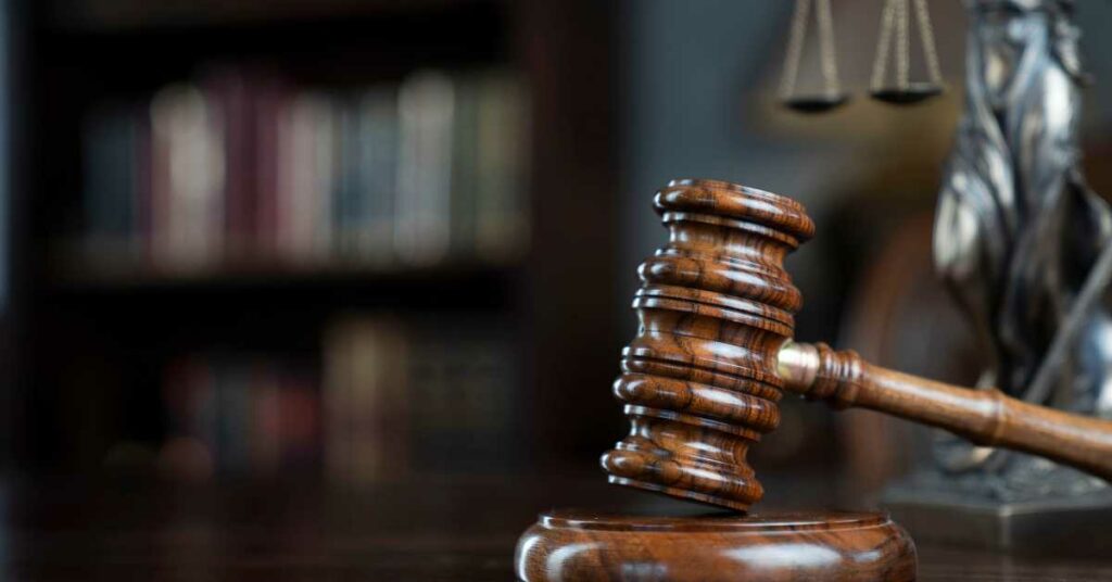 A Judge's gavel on a table with a dark background and a blurry bookshelf