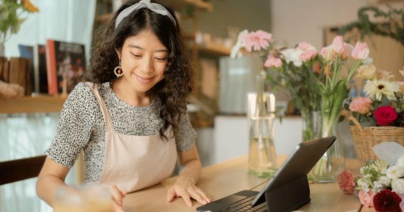 A self-employed florist working on a laptop in her shop