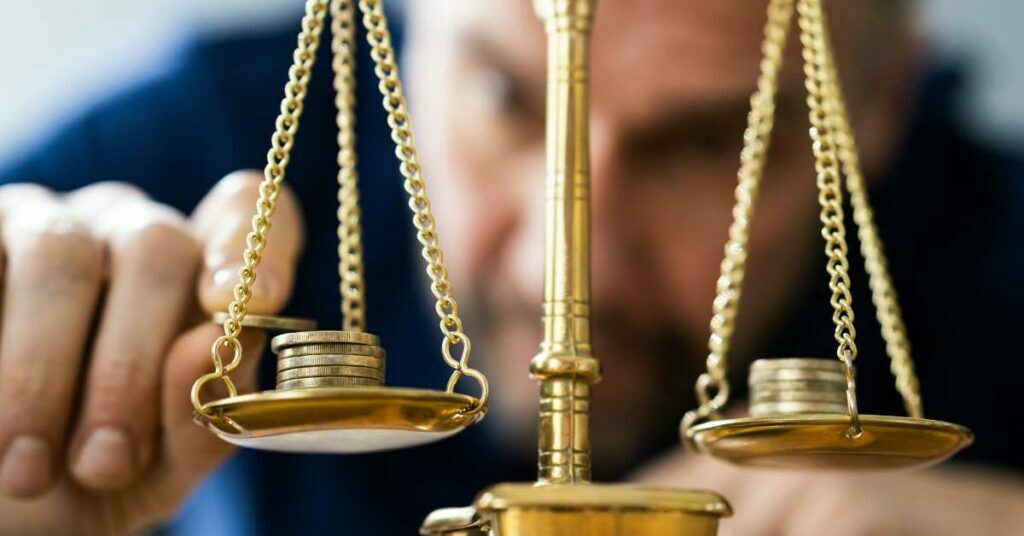 A bearded man weighing coins with a gold colored old school scale as if weighing different types of loans