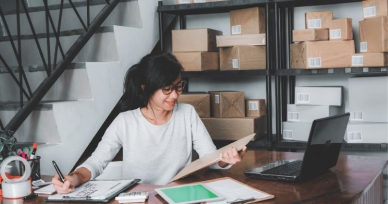 A self-employed woman filling out forms for sending packages from her webstore